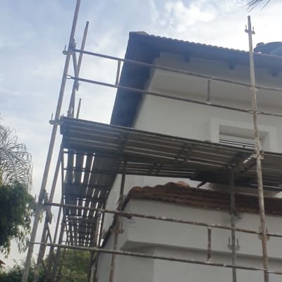 פיגומים לצד בניין לבן עם גג רעפים