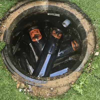 פתח ביוב עם צינורות כתומים ושחורים