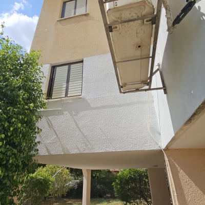 פיגום תלוי ליד בניין עם חלונות ועצים