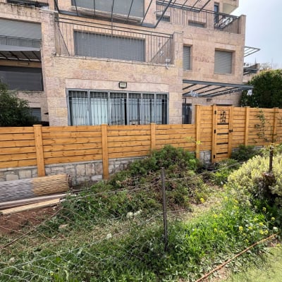 גדר עץ עם שער ליד גינה קטנה