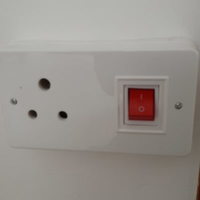 שקע חשמלי עם מתג אדום על קיר לבן