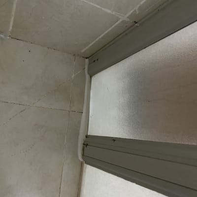 פינה של מקלחון עם אריחים ודלת זכוכית