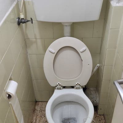 אסלה עם מיכל הדחה וצינור מים מחובר