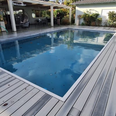 בריכת שחייה עם דק עץ מסביב לבית פרטי