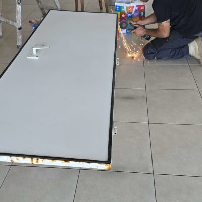 אדם עובד על דלת עם כלי חיתוך, ניצוצות עפים