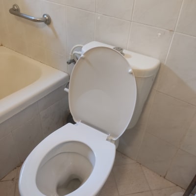 אסלה פתוחה ליד אמבטיה עם ידית אחיזה