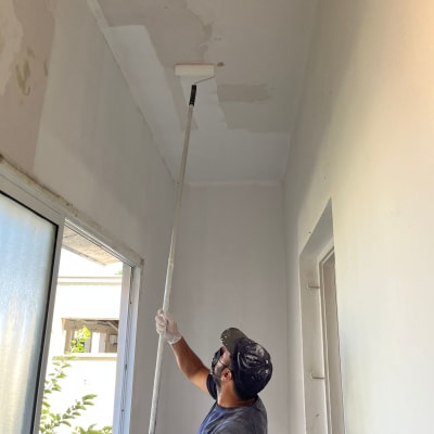 אדם צובע תקרה עם רולר על מוט ארוך