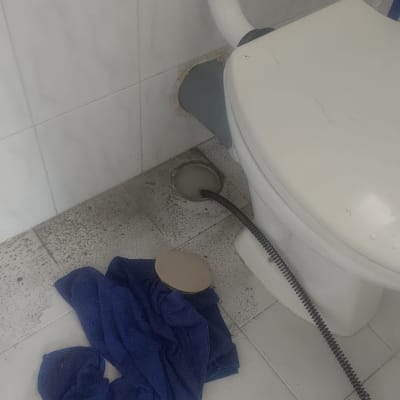 אסלה עם צינור ניקוז, מגבת כחולה על הרצפה