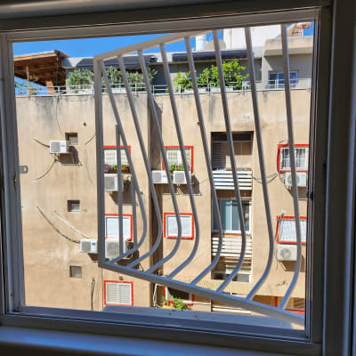 סורגי חלון לבנים במסגרת חלון פתוחה