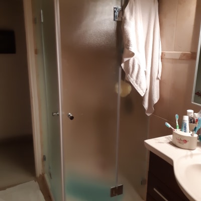 מקלחון זכוכית עם מגבת תלויה על הדלת