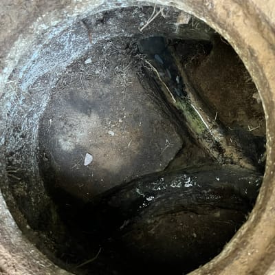 פתח ביוב עם צינור מים חשוף ואדמה לחה