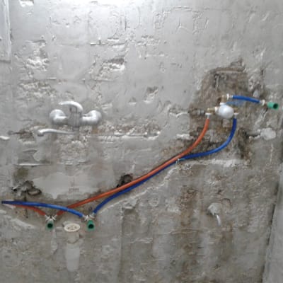 צנרת מים חשופה על קיר בטון בשיפוץ