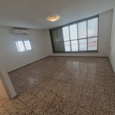 חדר ריק עם רצפה נקייה ותריסים סגורים