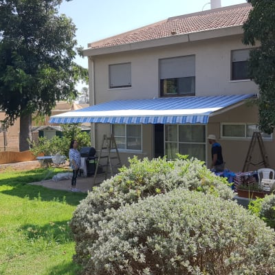 סוכך פסים כחול לבן מותקן על קיר בית