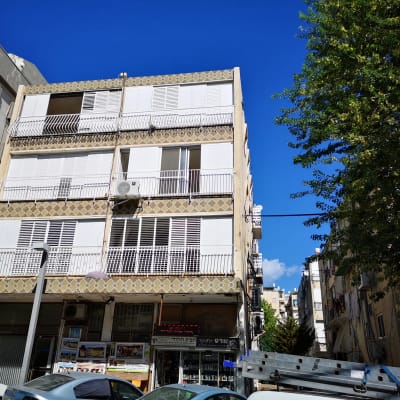 בניין עם תריסים לבנים ומעקות ברזל