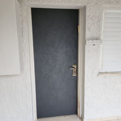 דלת אפורה עם ידית מתכת על קיר לבן