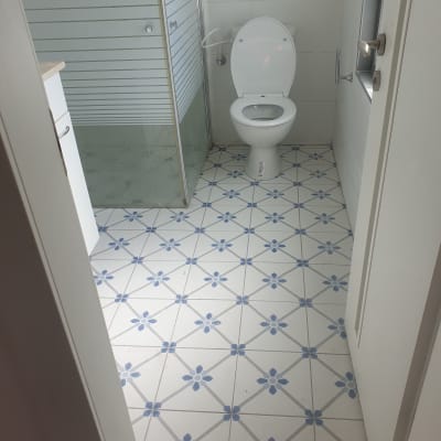 חדר אמבטיה עם רצפת אריחים מעוצבת ושירותים