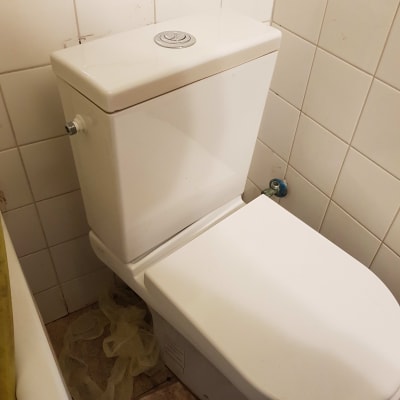 אסלה לבנה עם מיכל הדחה בחדר אמבטיה