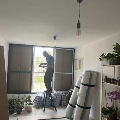 חשמלאי עומד על סולם ומתקין נורה בתקרה