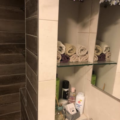 מדף זכוכית עם מגבות וכלי טיפוח בחדר אמבטיה