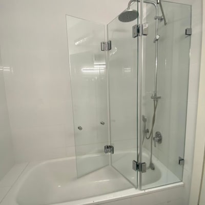 מקלחת עם דלתות זכוכית ואמבטיה לבנה