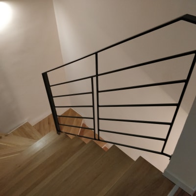 מעקה מתכת שחור במדרגות עץ