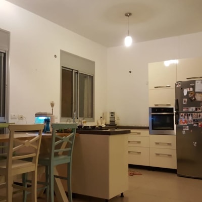 מטבח עם שולחן עץ, כיסאות, מקרר ותנור