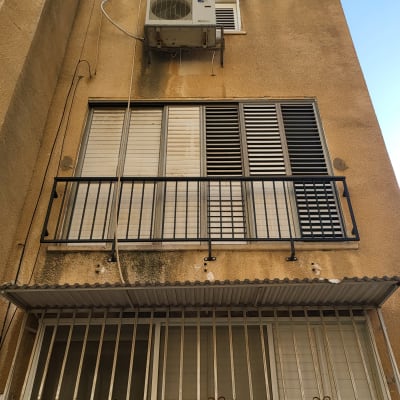 חלונות עם תריסים ומסגרת מתכת על קיר בניין