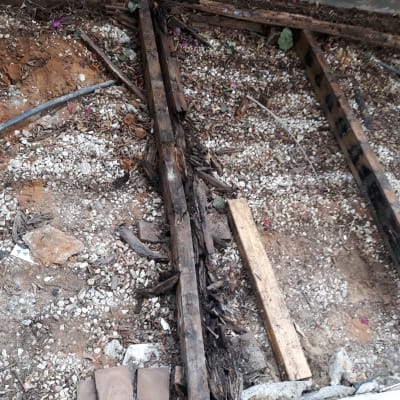 קרשים ישנים ורקובים בגינה עם חצץ ואדמה