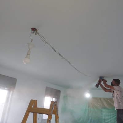 חשמלאי עובד על תקרה עם מקדחה חשמלית