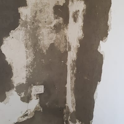 קיר עם טיח כהה ותיקונים בצבע לבן