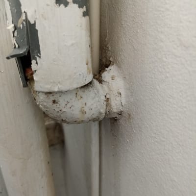 צינור מתכת חלוד עם חיבור לקיר