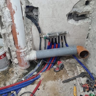 צינורות מים צבעוניים, קיר שבור, כלי עבודה על הרצפה