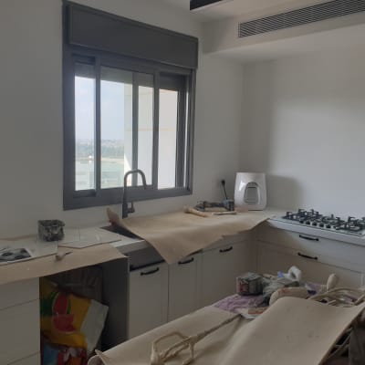 מטבח בשיפוץ עם ניירות מגן וכלי עבודה על השיש