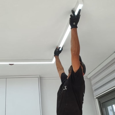 חשמלאי מתקין תאורה בתקרה עם סולם