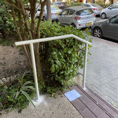 מעקה מתכת לבן ליד שביל מרוצף