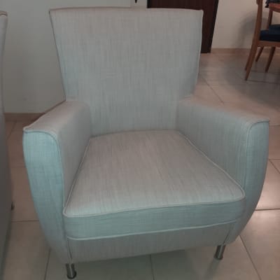 כורסה מרופדת בבד בהיר עם רגלי מתכת