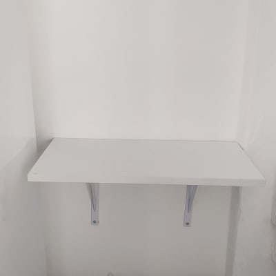 מדף עץ לבן עם תומכים על קיר לבן