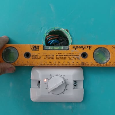 מד טמפרטורה מותקן על קיר עם פלס צהוב