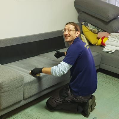 אדם מנקה ספה עם מברשת וכפפות שחורות