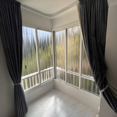 חלונות עם תריסים חצי פתוחים וילונות בצדדים