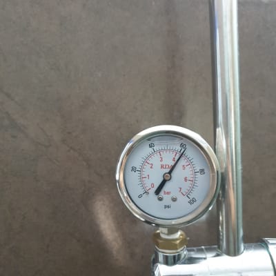 מד לחץ מים מחובר לצינור מתכת על קיר