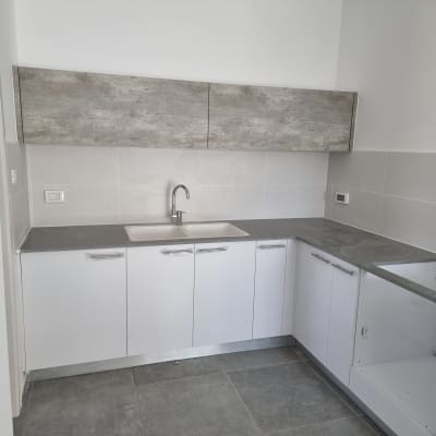 מטבח עם ארונות לבנים ומשטח עבודה אפור