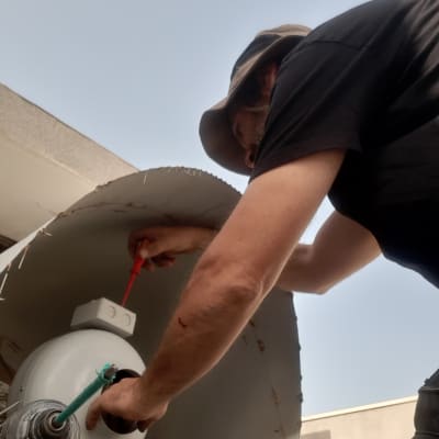 חשמלאי עובד עם מברג על מאוורר תעשייתי