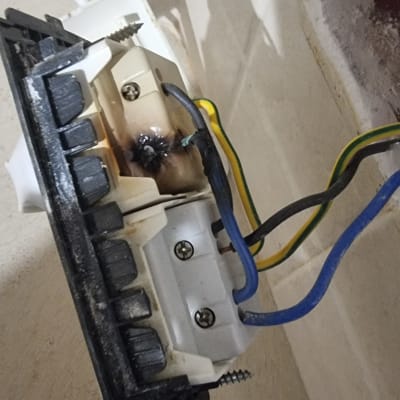 חוטי חשמל מחוברים לשקע עם סימני שריפה