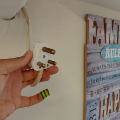 תקע חשמלי מוחזק ביד ליד קיר