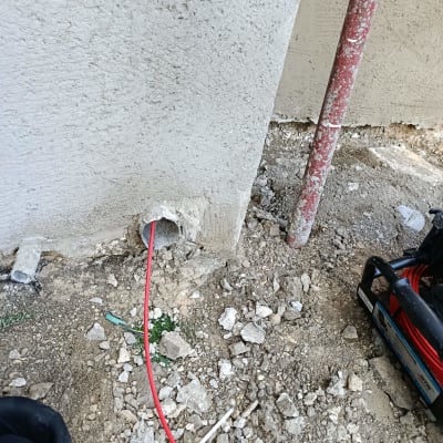 צינור אדום יוצא מקיר לתוך האדמה
