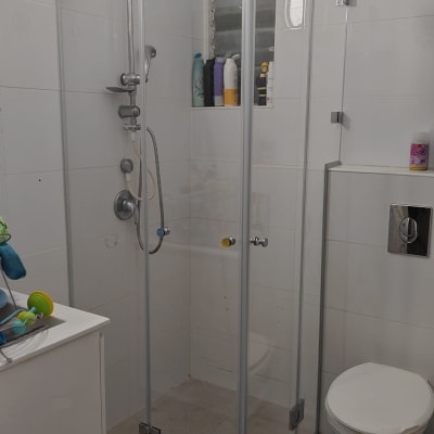 מקלחון זכוכית עם ראש מקלחת עגול ומדף בקבוקים