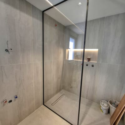 מקלחון זכוכית עם קיר אריחים אפורים