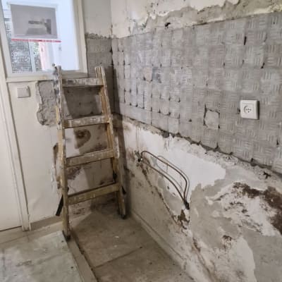 קיר מתקלף עם סולם עץ וחוטי חשמל חשופים